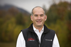 Photo of Barry Pius in a Stowe Mountain Resort vest and white collared shirt, mountainscape in the background