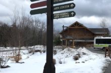 Spruce Peak in the snow with a sigh with arrows leading the way to attractions.