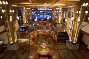 The Lodge at Spruce Peak main lobby with lights and birch trees lining a large seating area.