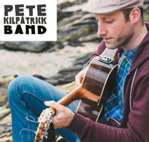 Portrait of Pete Kilpatrick seated playing guitar