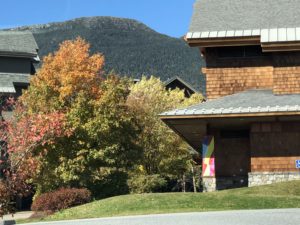 Theatre in Fall with foliage and Mt. Mansfield in the background, banner on column by artist Rob Hitzig