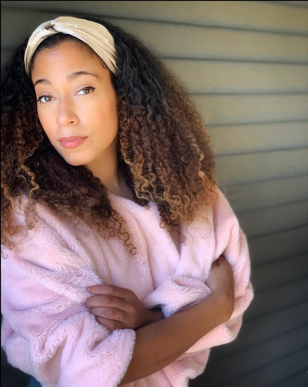 Myra Flynn Image of singer Myra Flynn, a bi-racial woman wearing a pink jacket standing against a beige wall with her arms crossed.